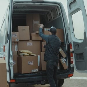 Contacto Mudanzas Málaga | Mudanzas en Calle Mágica. A courier organizing boxes in a delivery van for shipment on a cloudy day.